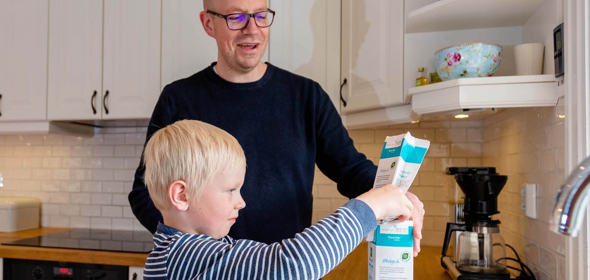 Gutt bretter drikkekartonger sammen med pappa